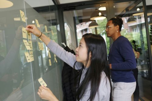 two people arranging sticky notes on a board