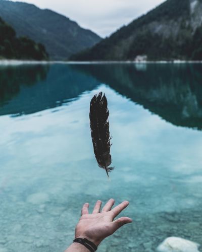 a hand reaching toward a clear lake